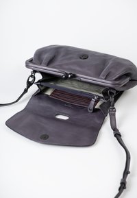 Borsa in pelle viola con chiusura a morsetto, caratterizzata da una fodera a righe e tasche interne. Include una tracolla rimovibile per maggiore versatilità.