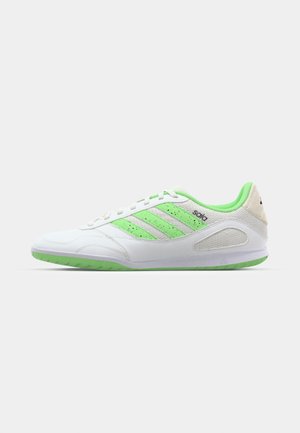White athletic shoe with green accents and three stripes, featuring a textured material, rubber sole, and a padded collar.