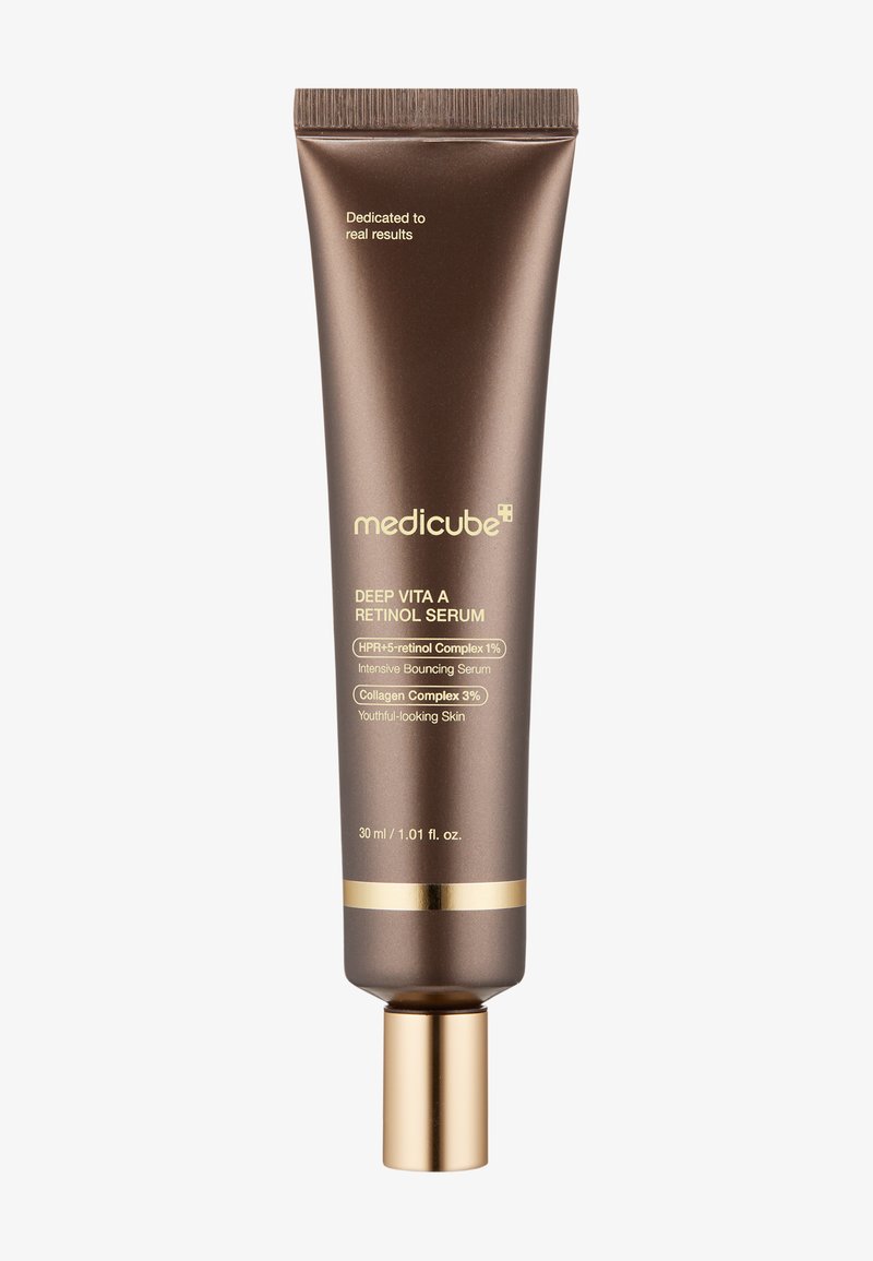 Brun klemmetube med en guldkapsel, mærket "Deep Vita A Retinol Serum," med tekst om ingredienser og volumeninformation.