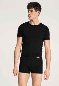 Zwarte getailleerde T-shirt met korte mouwen en een ronde hals, gecombineerd met zwarte boxershort ondergoed, beide gemaakt van een gladde, rekbare stof.