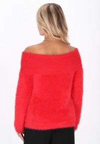 Roter schulterfreier Pullover aus flauschigem, strukturiertem Stoff. Gerippter Ausschnitt und lange Ärmel. Eng an den Schultern, lockere Körperform.