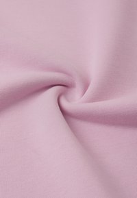 Jasnoróżowa, ribbed tkanina o gładkiej, miękkiej teksturze, z widocznym skrętem, który podkreśla jej elastyczność i wzór dzianiny.