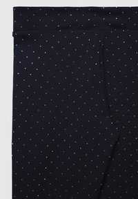 Leggings blu navy realizzati in un materiale morbido, caratterizzati da una vestibilità regolare, una vita elastica e motivi di punti argentati sparsi sulla superficie.