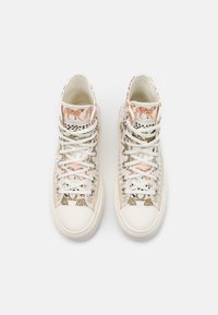 High-top sneakers featuring a mix of white canvas and animal print patterns in shades of beige and light pink, with white laces and silver eyelets.