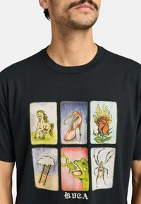 Camiseta negra con seis estampados gráficos coloridos: un caballo, un tacón alto, una rosa llameante, una nube con una escalera, una rana verde y una araña.