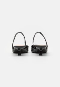 Mustad musta nahast slingback-kontsaga, kitsenevate ruudukujuliste kontsade ja avatud seljatoega disain. Lame alus ja minimaalne kaunistus.