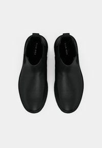 Melnas bezkurpes ar gludu ādas faktūru, apaļu purngalu, minimālām šuvēm un cilpu uz papēža, kas nodrošina vieglu uzvilkšanu.