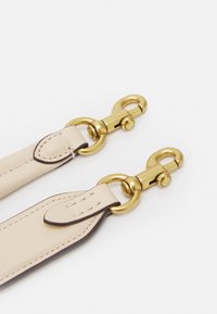 Beige läderremmar med guldfärgad hårdvara, med svängbara hummerklipp och sömnadsdetaljer, slät textur och rundade kanter.