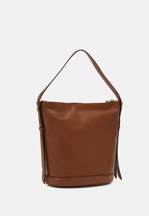 Brązowa skórzana torba typu bucket z regulowanym paskiem na ramię i bocznymi klamrami na białym tle.