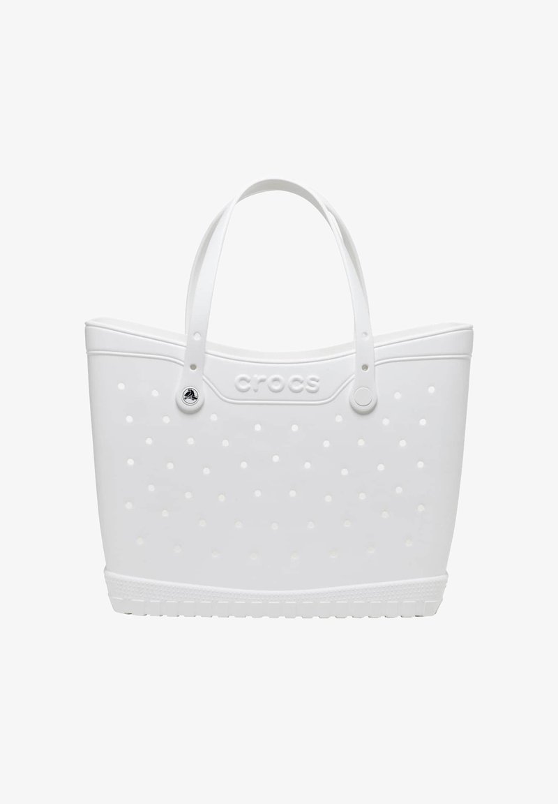 Weiße Crocs Tragetasche mit kleinen Belüftungslöchern, zwei Griffen und eingeprägtem Crocs-Logo in der Mitte vorne.