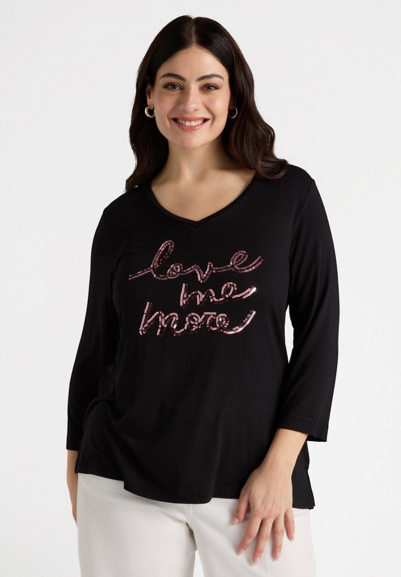 Schwarzes Langarmshirt mit V-Ausschnitt und einem pinken Pailletten-Graphic "love me more" auf der Vorderseite. Glattes Material mit einer lässigen Passform.