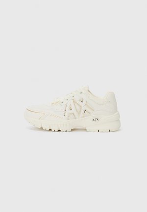 Sapatos atléticos brancos com parte superior em malha e couro sintético, apresentando um detalhe do logótipo, painéis laterais texturizados e um design de sola robusta.