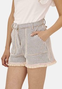 Pantalones cortos de tela tejida con un patrón de cuadros azul y crema, con cintura ajustable con cordón, bolsillos laterales y un dobladillo deshilachado.