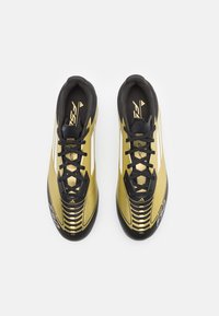 Scarpe da calcio oro e nere dal design elegante, con una tomaia testurizzata, lacci neri e distintivi accenti bianchi.