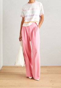 Jersey de rayas en colores pastel, combinado con pantalones rosas de cintura alta y con pliegues. Incluye un bolso blanco y zapatos de tacón.