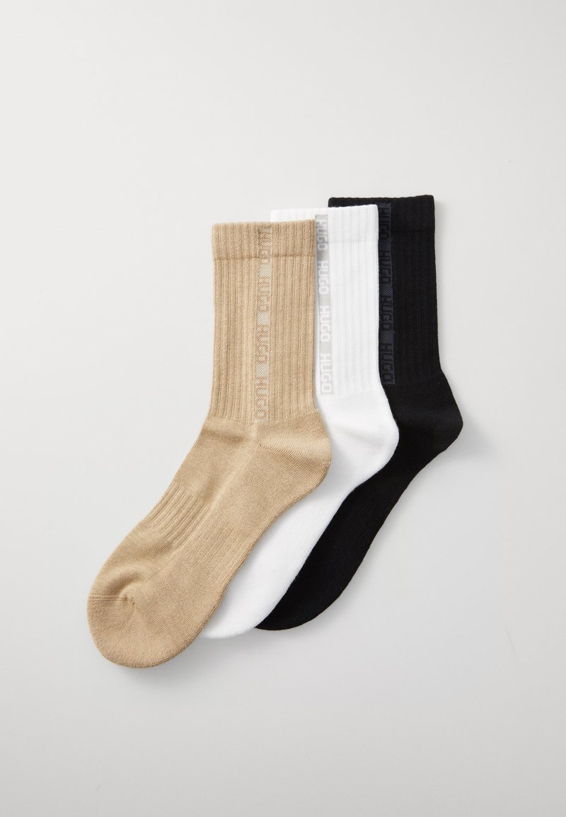 Drei Paar Socken: beige, weiß und schwarz. Gerippte Struktur, knöchellang, mit "HUGO"-Logo in kontrastierenden Farben auf jedem Paar.