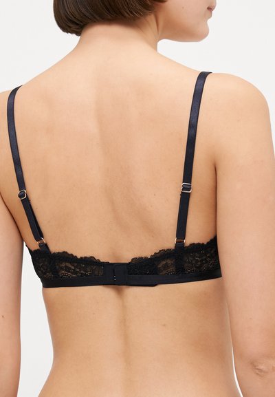 Black lace bralette featuring a sheer lace band, adjustable satin straps, and a hook-and-eye closure at the back. Smooth texture.