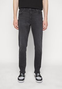 Vaqueros gris oscuro de corte slim, confeccionados en denim. Cuentan con cinco bolsillos y una cinturilla clásica. Combinados con zapatillas negras y blancas.