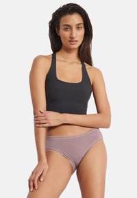 Sort crop top med brede stropper og firkantet udskæring, kombineret med lyse mauve trusser med blondedetalje og logo ved linningen.