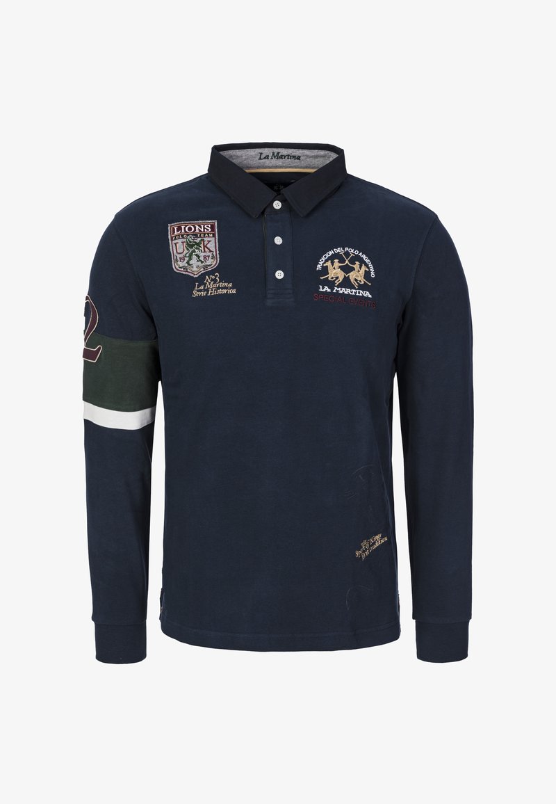 Granatowa koszulka polo z długim rękawem, z haftowanymi naszywkami, kołnierzykiem i listwą z guzikami. Posiada zielone i białe akcenty na rękawach i na dole.