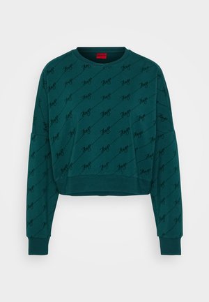 Teal cropped sweatshirt met lange mouwen, voorzien van een herhaald zwart scriptpatroon. Ribgebreide manchetten en halslijn, label zichtbaar in het rood.