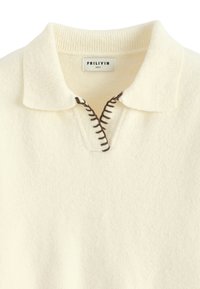 Pull couleur crème avec un col à revers, fermeture à zip partielle et détails de couture marron contrastants sur la patte de boutonnage. Texture douce.