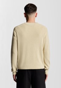 Lys beige ribbet langærmet sweater med rund halsudskæring og tætsiddende manchetter, der har et tekstureret stof og en afslappet pasform.