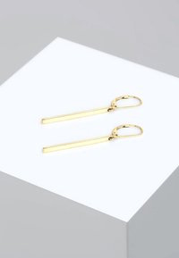 Kuldse tooni kõrvarõngad, millel on õhukesed ristkülikukujulised vardad, poleeritud viimistlusega ja tagant lukustuv sulgur. Lihtne ja kaasaegne stiil.