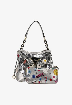 Sølvglitrende håndtaske med sort rem, pyntet med tegneserie-patche og farverige klistermærker. Inkluderer en matchende lynlåspung.