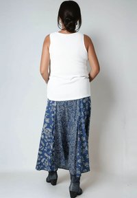 Witte geribbelde tanktop gecombineerd met een blauwe rok met paisleypatroon. De rok heeft bloemmotieven en een vloeiende, enkellange vorm.