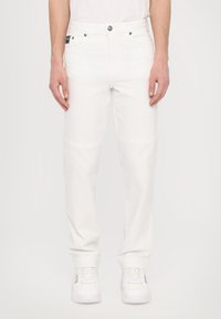 Pantalon en denim blanc avec une coupe droite, design à cinq poches et coutures subtiles. Assorti à des baskets blanches pour un look décontracté.