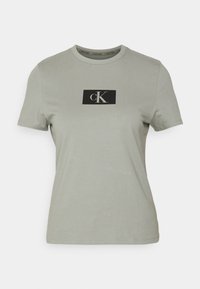 Camiseta de manga corta verde claro hecha de algodón. Presenta un parche rectangular negro con letras "cK" en blanco en la parte delantera.