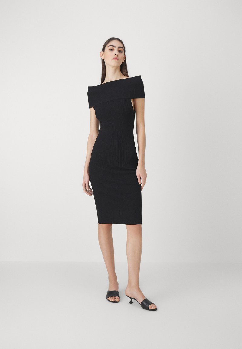 Rochie neagră cu umerii la vedere, cu o siluetă ajustată, textură ribbed, până la genunchi, asociată cu mules cu toc deschis la vârf, negre.