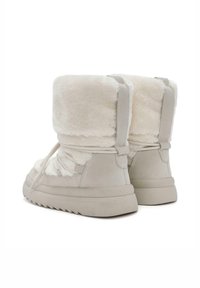 Botas de imitación de piel de piel sintética con interior de piel sintética, exterior de ante, punta redondeada y suela de goma texturizada. Presentan cordones elásticos y un alto cuello.