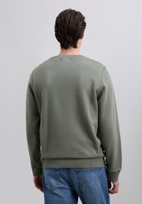 Long-sleeve crewneck sweatshirt in olive green, made of textured fabric with a fitted waistband. Features side seams and ribbed cuffs.