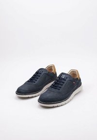 Zapatillas de cuero azul marino con detalles en tono marrón, suela de goma blanca y cordones en azul oscuro. Incluyen costuras contrastantes y una etiqueta con el logo.