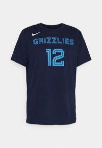 Mørkeblå bomulds T-shirt med korte ærmer, med teksten "GRIZZLIES" og nummeret "12" i lys blå skrift. Nike-logo på venstre skulder foran.