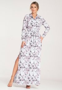 Kwiatowa sukienka maxi w białych i pastelowych odcieniach, z długimi rękawami, paskiem w talii i bocznym rozcięciem. Posiada kołnierz oraz delikatne wzory kwiatowe.