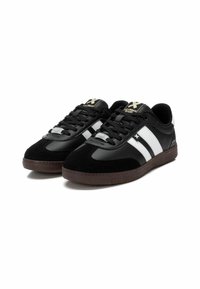 Black and white athletic shoes with a suede and synthetic leather upper, rubber sole, and contrasting stripes on the sides.