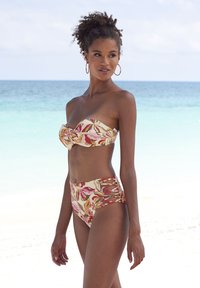 Kvetinový bikiny v pink, béžových a zelených odtieňoch. Top bez ramienok s detailom twist a vysoké spodné diely s bočnými výrezmi a krížovým dizajnom.