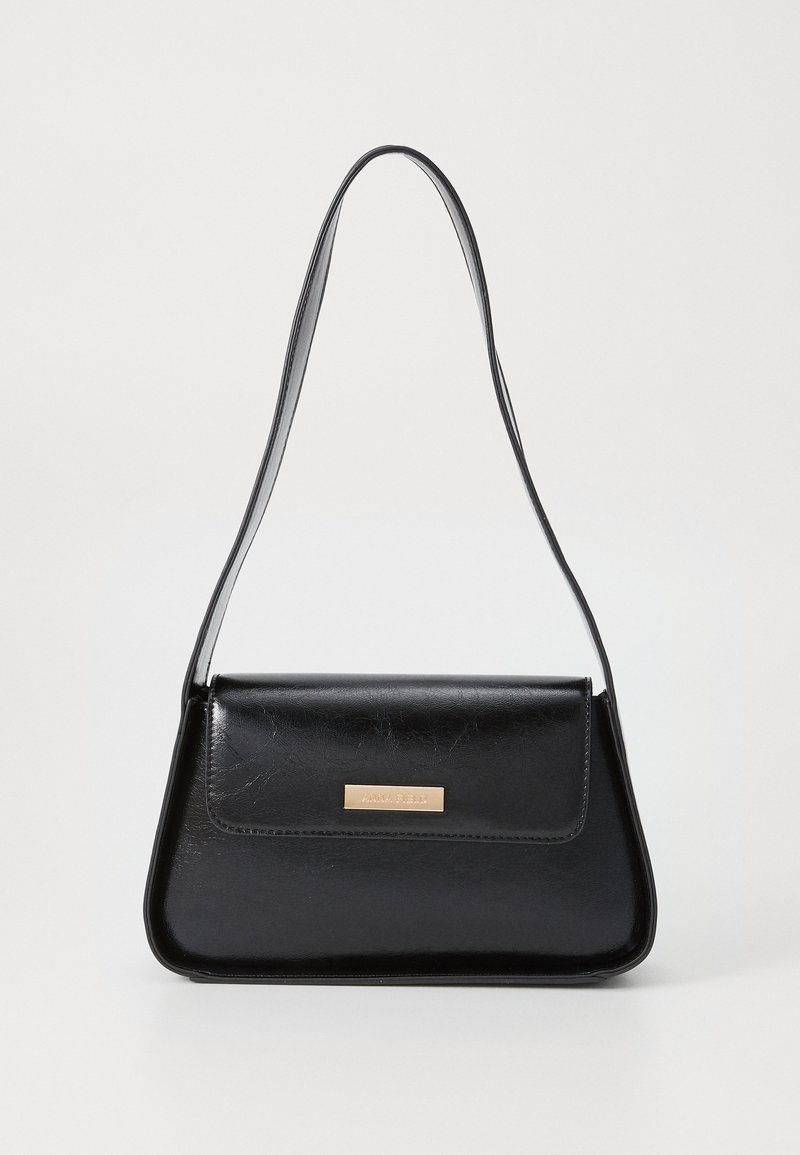 Black leather handbag with a structured triangular shape, slim strap, and gold-tone hardware featuring a logo plaque on the front flap.