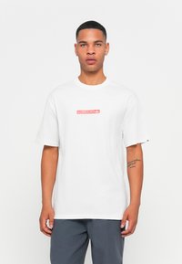 White cotton t-shirt featuring a rectangular red "QUIKSILVER" logo on the chest, short sleeves, and a relaxed fit.