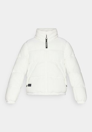 White puffer jacket with a high collar, zip front, and quilted texture. Features side pockets and a black brand tag on the hem.