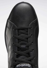 Black sneaker with a rounded toe, leather upper, mesh texture, and flat black laces. Features Reebok logo on the side in white.