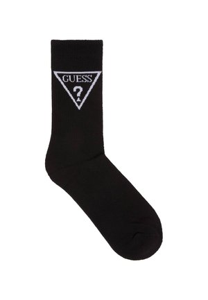 Zwarte sok met ribbelstructuur, voorzien van een witte driehoekige logo met "GUESS" en een vraagteken erin. Klassiek ontwerp, enkel-lange stijl.