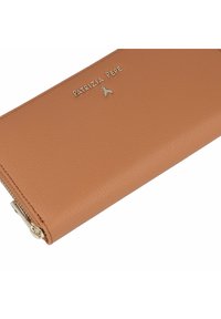 Cartera de cuero color cuero claro con superficie texturizada, que presenta un logo de marca y herrajes en tono dorado. Cierre con cremallera a lo largo de un borde. Forma rectangular clásica.