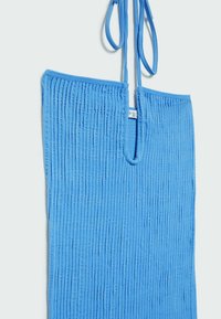 Haut à col licou en tissu bleu à côtes avec un décolleté en U et de fines bretelles à nouer, présentant des lignes texturées verticales sur toute la surface.