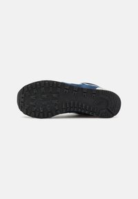 Black rubber sole of a shoe with a textured grip pattern. Upper part features dark blue material. Overall sturdy and durable design.