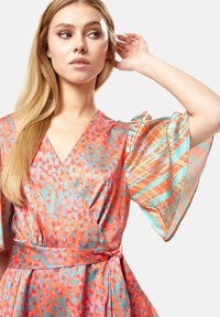 Colorful wrap dress in orange with blue and pink patterns, featuring flowing sleeves and a cinched waist for a structured fit.