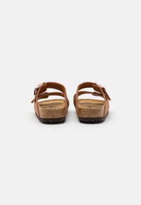 Brown leather sandals with two adjustable straps, cork footbed, and textured rubber outsole, showing back view.